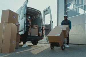 Two couriers load boxes into a van for shipment, showcasing logistics and teamwork.