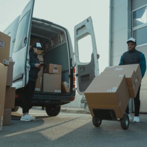 Two couriers load boxes into a van for shipment, showcasing logistics and teamwork.