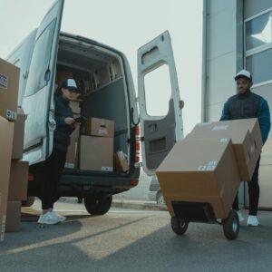 Two couriers load boxes into a van for shipment, showcasing logistics and teamwork.